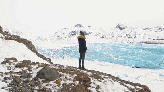 Vatnajokull冰岛山上的冰川一名穿着黑色夹克的年轻游客在冰岛巨大的冰川上漫步