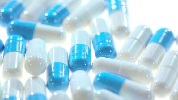 药药白色和蓝色的胶囊在白色的桌子上旋转的特写