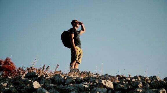 一个背着背包的男人在山上眺望远方健康积极的生活方式
