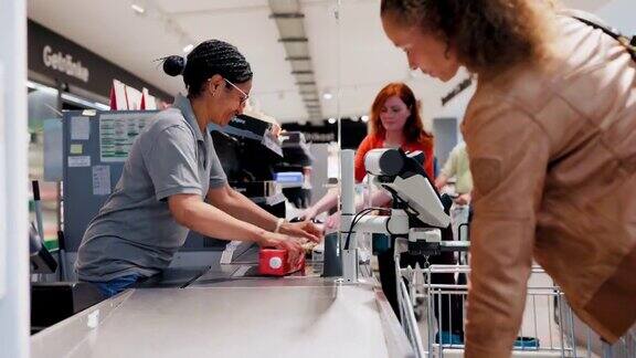 女收银员在收银台为顾客扫描商品