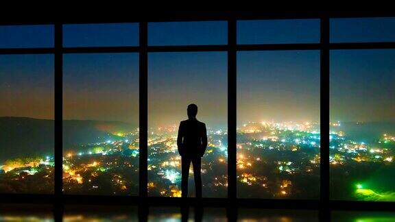 这个男人站在全景窗户旁以雾蒙蒙的城市为背景时间流逝