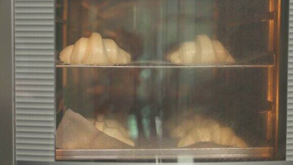 一个牛角面包在工业加热烤箱中烘烤的特写牛角面包在烘焙屋的制造