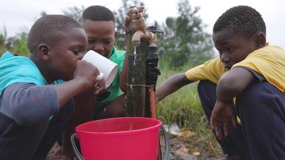 年轻的非洲黑人男孩坐在公共水源点饮水水危机贫困气候变化全球变暖干旱