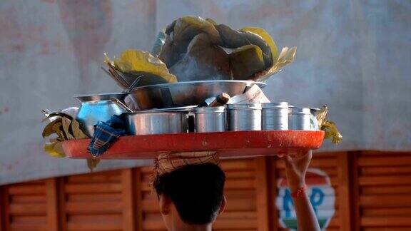 一个年轻的印度人头上顶着一盘现成的食物走在德里的大街上