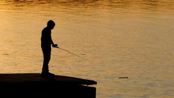 一个年轻渔夫拿着钓竿的剪影