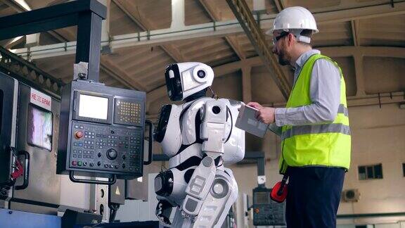 工厂工人使用设备中的平板电脑控制一个机器人