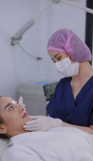 女医生戴着卫生手套戴着发帽给美丽年轻的亚洲医疗服务注射抗皱纹和良好的脸型的Butolinum毒素和填充剂