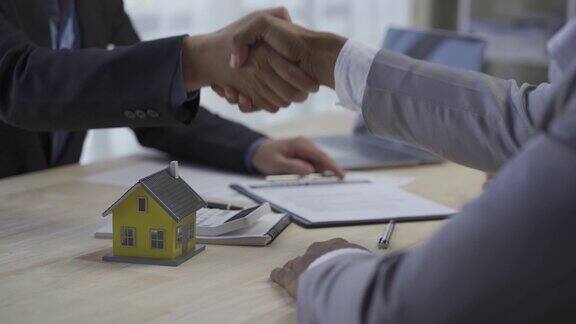 房屋中介和买家签订新房合同并与客户握手解释他们感兴趣的房产、住房项目的细节