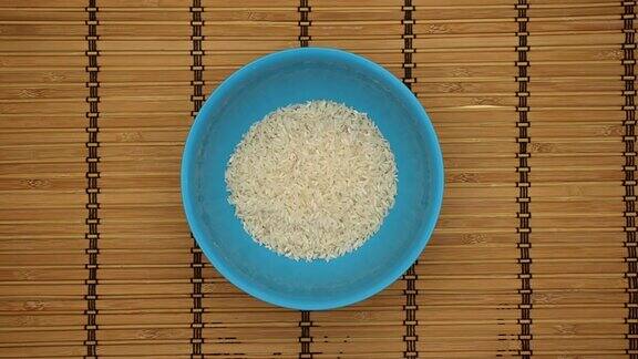 米饭在一个蓝色的盘子在木背景-停止运动
