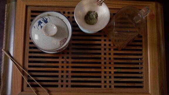 茶爱好者的手从木制桌子上拿起绿茶杯