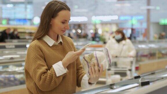 一名女子在超市购物用智能手机扫描条形码