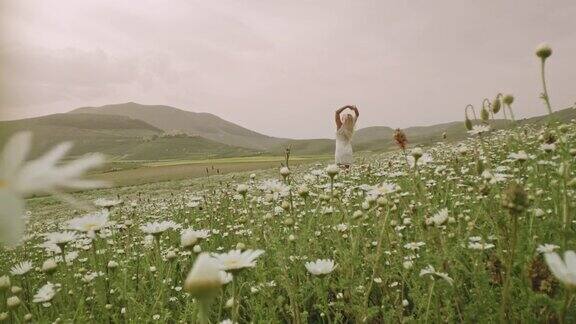 在意大利翁布里亚卡斯泰鲁西奥田园诗般的雏菊草地上怀抱着无忧无虑的女人