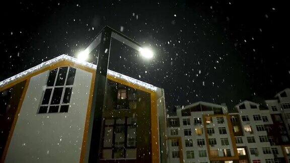 雪落在街灯的背景在城市的一个公寓房子晚上