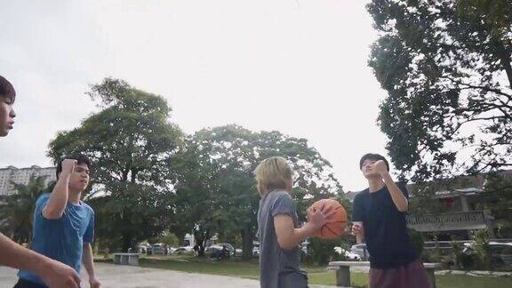 慢动作背光Z一代亚洲华人少年挑战球员和投篮在周末早上练习篮球比赛的朋友