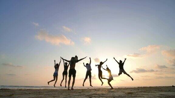 日落时分朋友们在海滩上跳跃的剪影慢动作