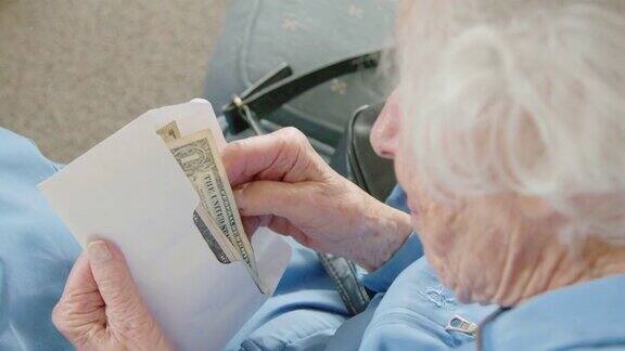 一位年长的白人妇女看着一张一美元的钞票数着信封里的现金