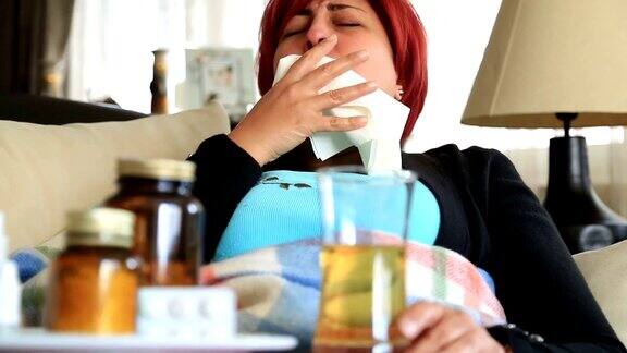 一个生病的女人躺在沙发上咳嗽