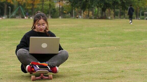 女大学生在校园里的草坪上用笔记本电脑