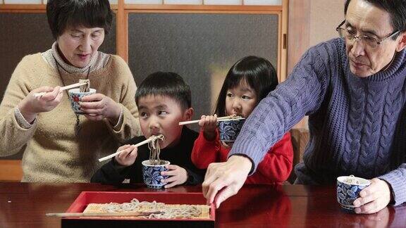 日本的祖父母和孙辈在日本的房间里吃着荞麦面