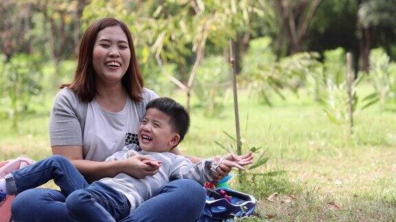 亚洲母亲和儿子一起在花园公园笑