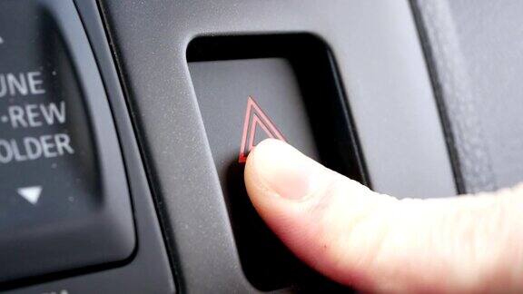 女人的手按下了汽车仪表盘上的停止紧急指示灯按钮