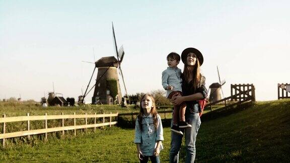 一个白人女人带着两个孩子在风车农场附近妈妈小男孩和可爱的女孩一起探索周围的环境4k
