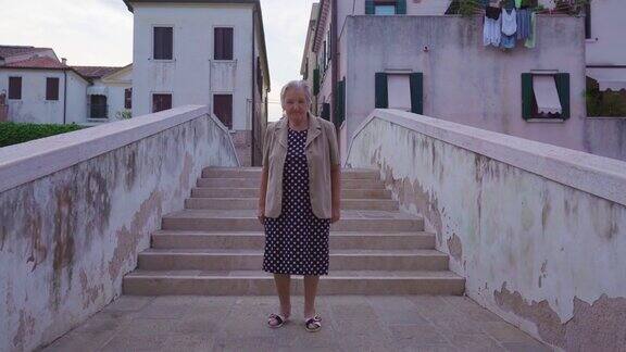 一位年长的女游客站在Chioggia的城市桥上
