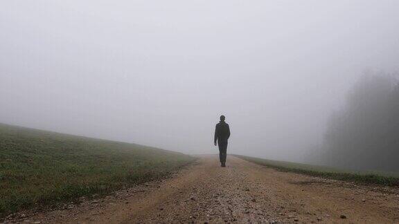 一个人走在雾蒙蒙的乡村道路上的背影