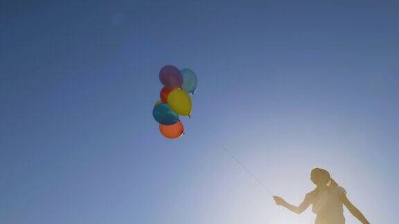 一个女孩的剪影在蓝天上玩气球