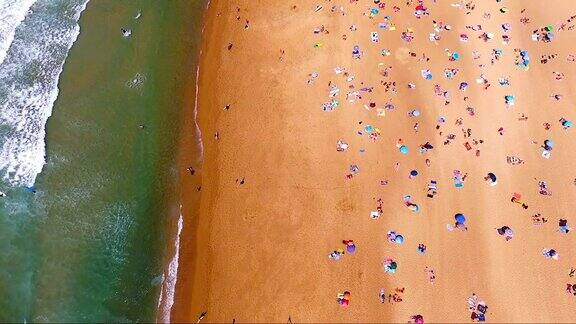 鸟瞰图的海滩伞在海滩的右边和大海在左边在法国南部金色的沙滩上有很多人海浪来了又去
