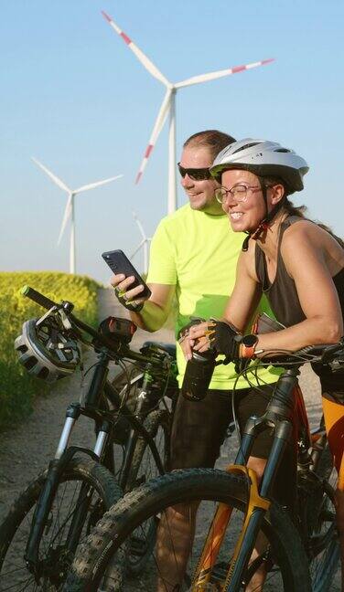 积极的成年夫妇骑自行车享受积极的生活方式和暑假在风车公园骑自行车时使用智能手机上的GPS导航应用程序讨论和选择旅行路线
