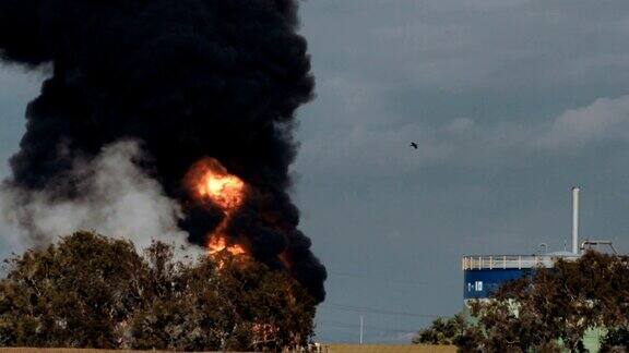 炼油厂事故-巨大的爆炸和火球上升浓重的黑烟笼罩着天空