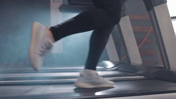 特写运动员在健身房里跑步机上跑步慢动作在跑步机上锻炼的白色运动鞋的侧视图低视人的腿训练在运动俱乐部