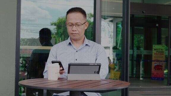 40-50岁的亚洲商人穿着休闲服装使用手机或智能手机