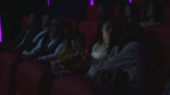一个亚洲中国女人在黑暗中看手机信息忽视和打扰她周围的观众