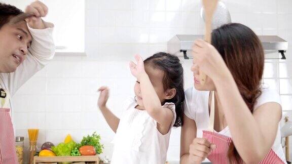 4k慢镜头年轻的亚洲父亲母亲和女儿快乐和有趣的烹饪在现代白色厨房女儿做饭时心情愉快