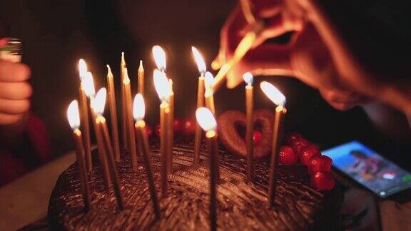 带蜡烛的生日蛋糕近距离的女性手燃烧生日蜡烛派对蛋糕甜蜜的生日庆祝活动女手用打火机点燃蜡烛火