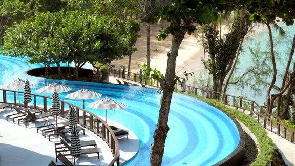 阳光休息室与伞或阳伞附近美丽的游泳池在现代热带豪华度假村旅游概念泰国旅游和暑假海上度假