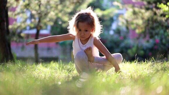可爱的小女孩在公园的草地上做瑜伽运动