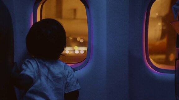 幼童正在通过窗户看全景飞机