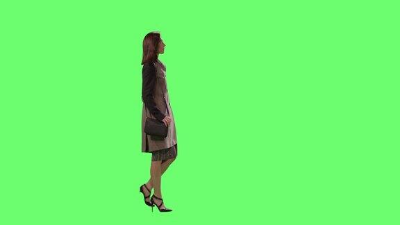 休闲黑发女性是走在一个模型的绿色屏幕在背景