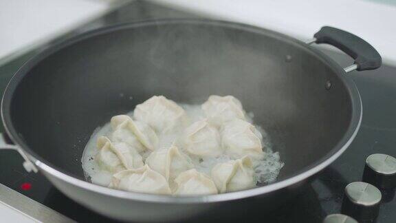 近距离的中国奶奶准备煮蒸汽中国饺子在烹饪锅在itchen