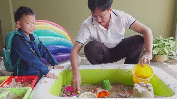 快乐的亚洲父子在家里玩沙子小朋友玩沙子玩具蒙台梭利教育与小朋友隔离选择性关注小朋友