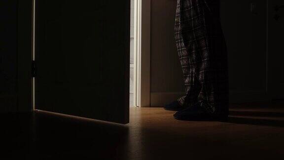 一个穿着睡衣的成年人在晚上走进浴室