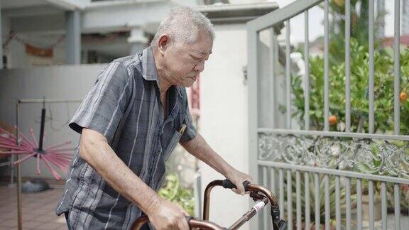 亚裔华裔老人使用移动助行器从前院走出来