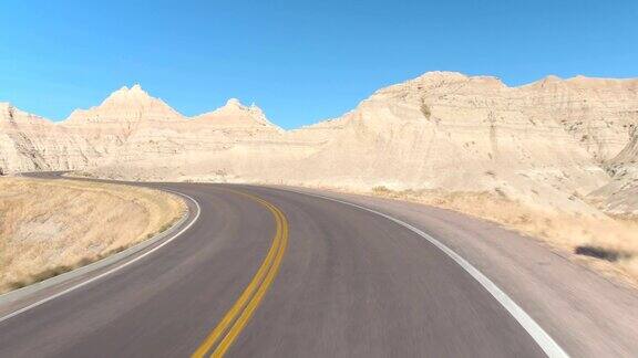 FPV:沿着空旷的道路行驶蜿蜒穿过广阔的Badlands山区沙漠