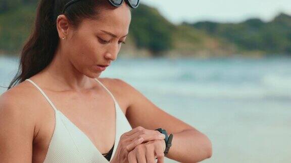 亚洲女性夏天在海滩上看智能手表
