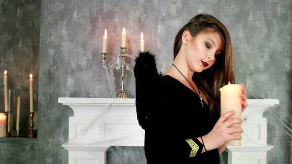 年轻的女巫拿着蜡烛万圣节庆祝神秘的气氛青少年穿着黑暗天使的服装