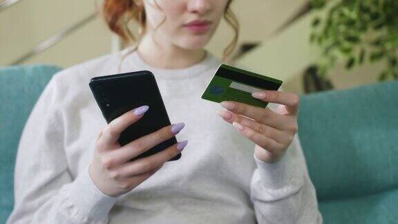 美丽的年轻女子用智能手机在线银行支付在家用信用卡购物