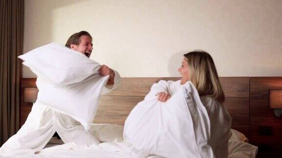 好玩的夫妇在床上打枕头仗